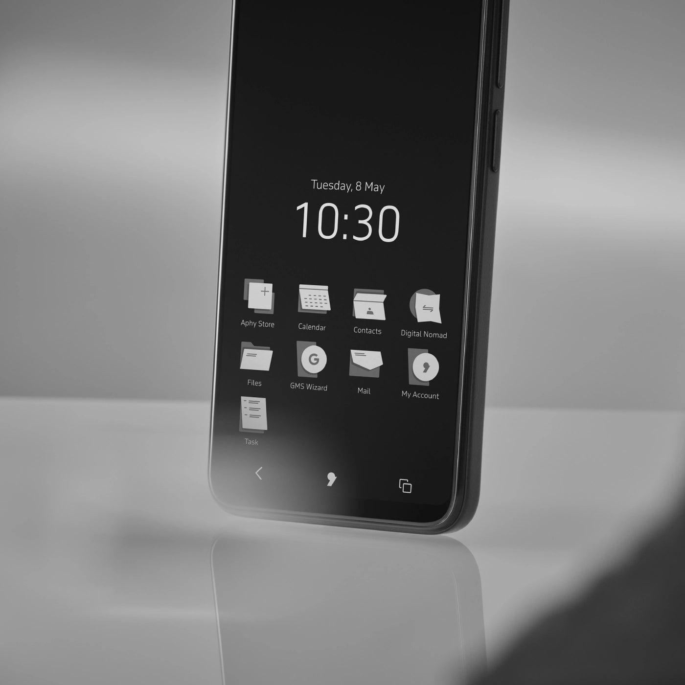 Close-up of the Punkt. MC02 smartphone showing its monochrome home screen with minimalist app icons and the time displayed as 10:30 on Tuesday, 8 May.
