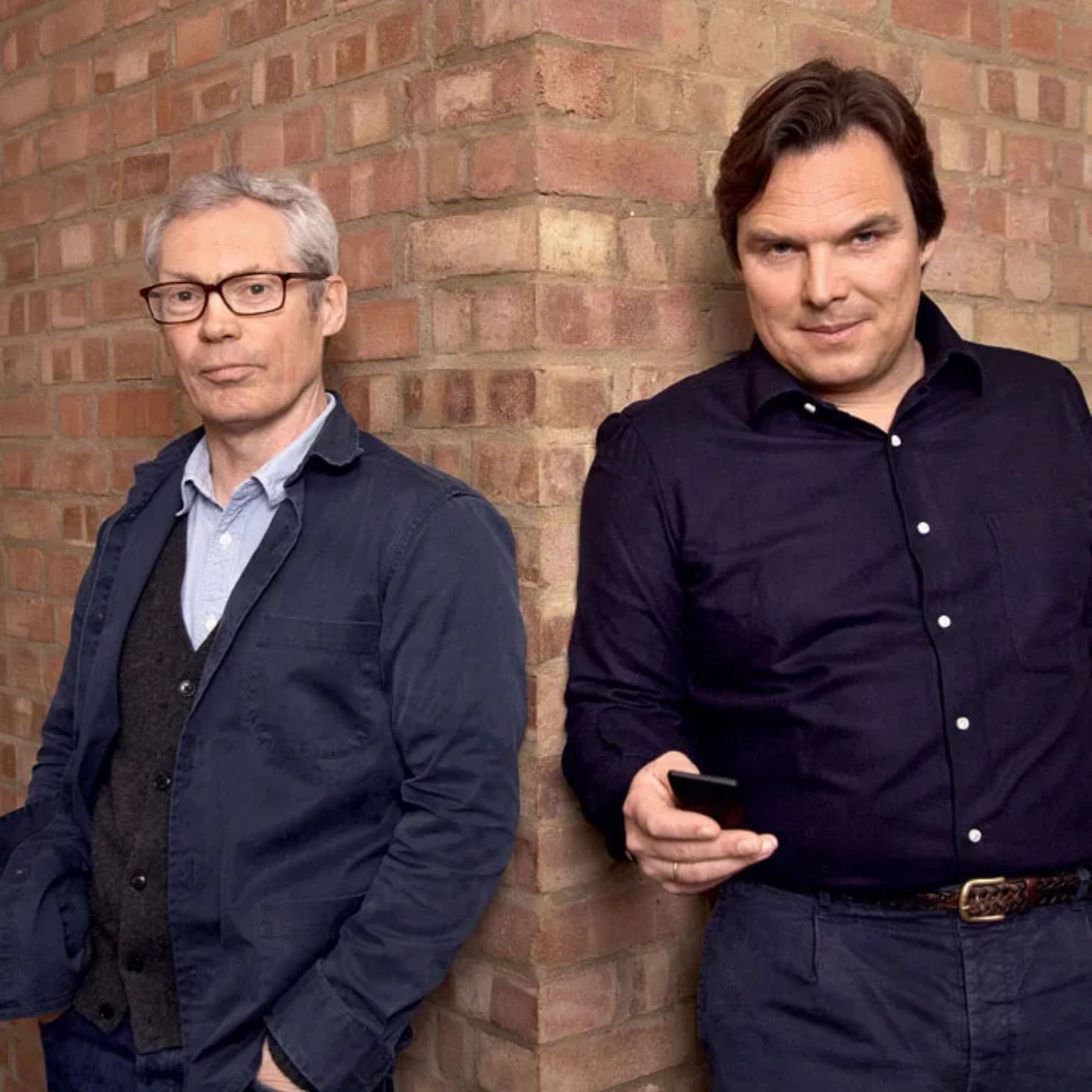 Jasper Morrison and Petter Neby standing against a brick wall, one holding a Punkt. MP02