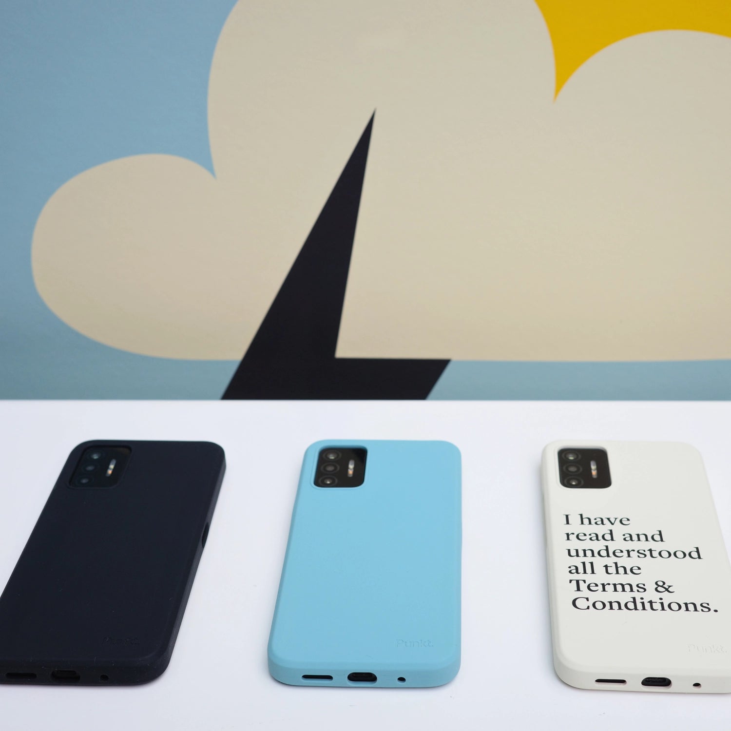 Punkt. MC02 protective cases in three colors – black, blue, and printed white – shown from the back on a white surface with abstract artwork behind.