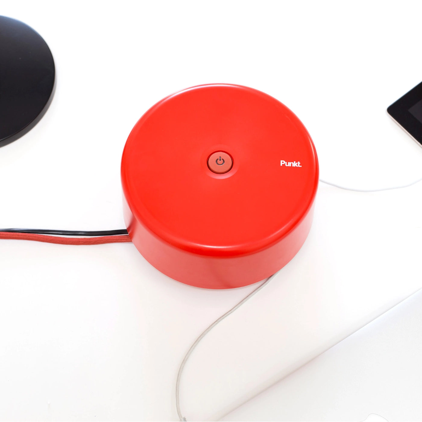 Top view of the red Punkt. ES01 power strip with its central power button visible, surrounded by charging cables.