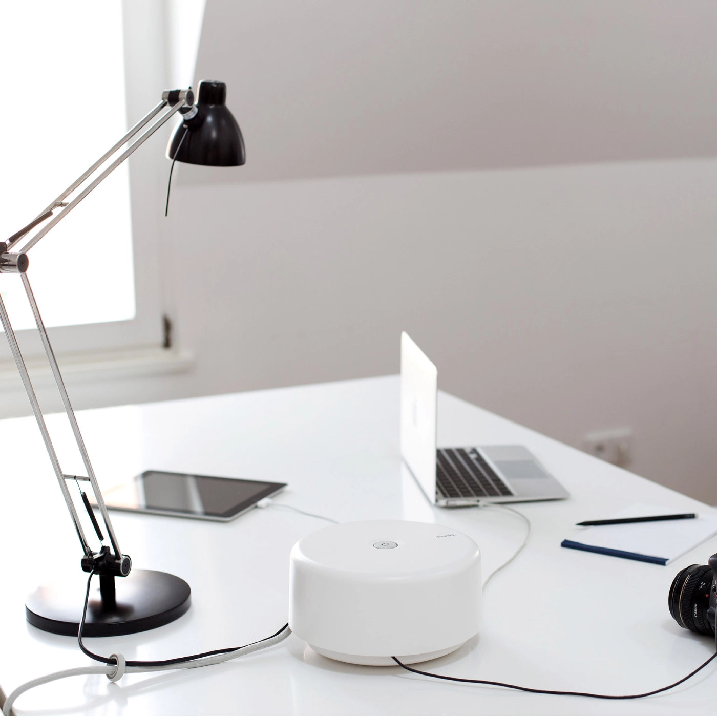 Punkt. ES01 power strip in white on a clean white table, connected to a camera and other electronics.