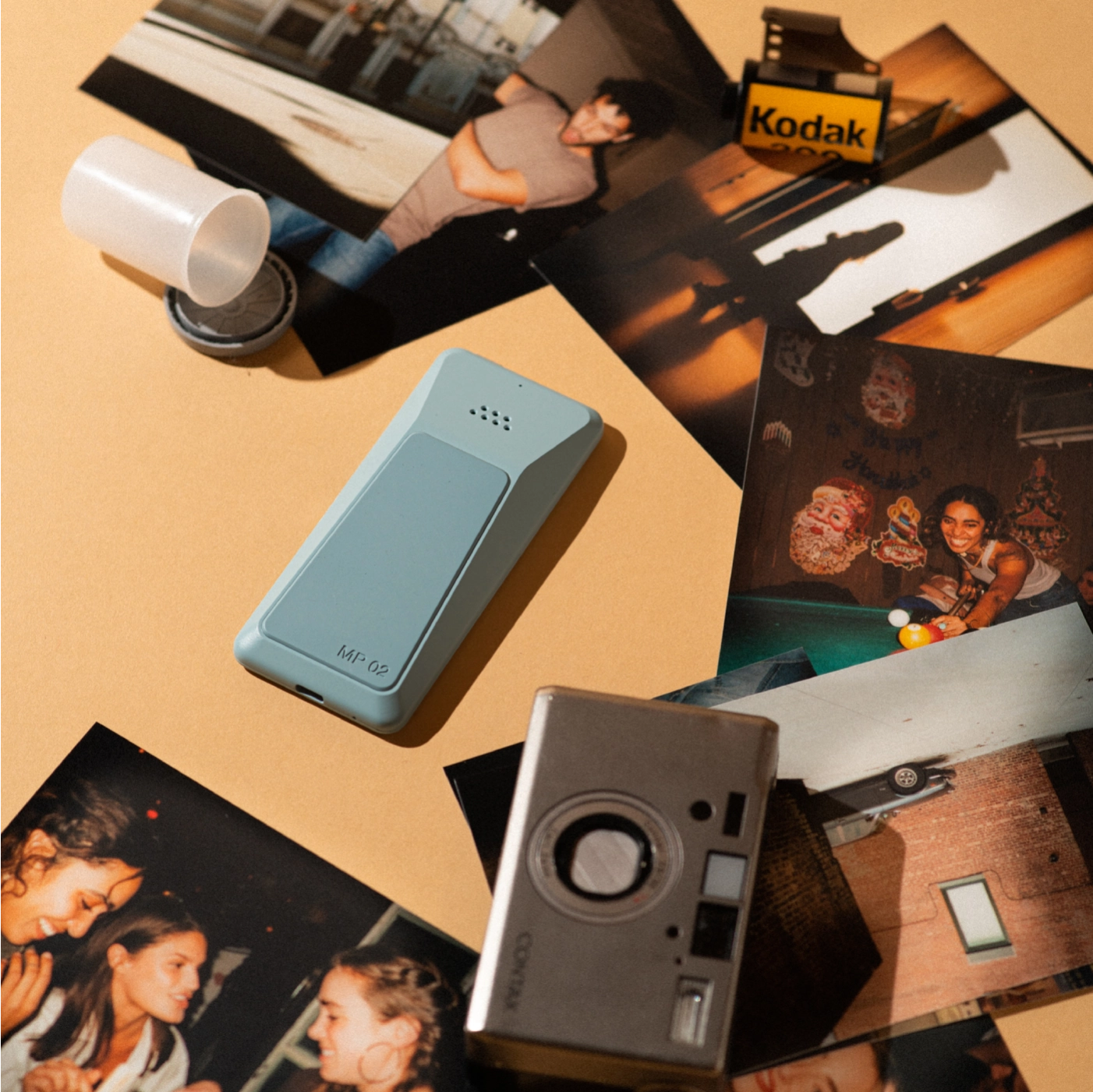 Back view of a blue Punkt. MP02 phone on a desk surrounded by printed photos, a film roll, and a vintage camera – evoking analog nostalgia and timeless design.