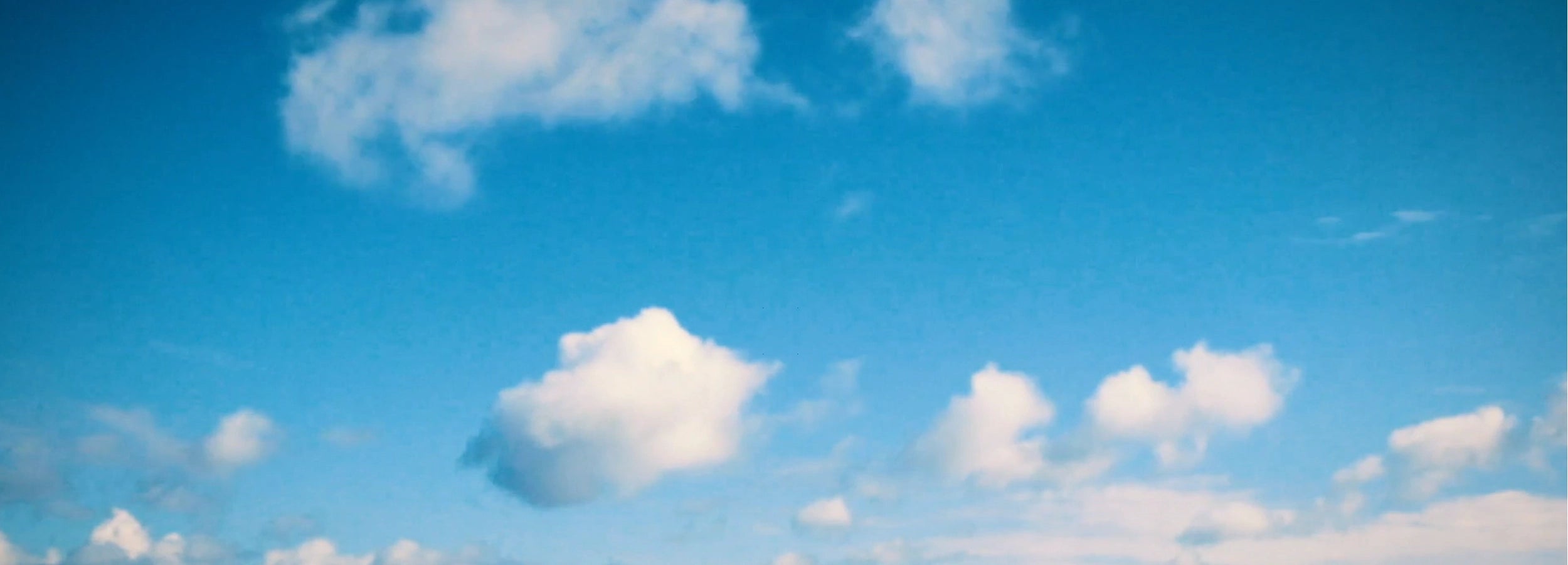 Bright blue sky with soft white clouds, evoking a serene and tranquil atmosphere.