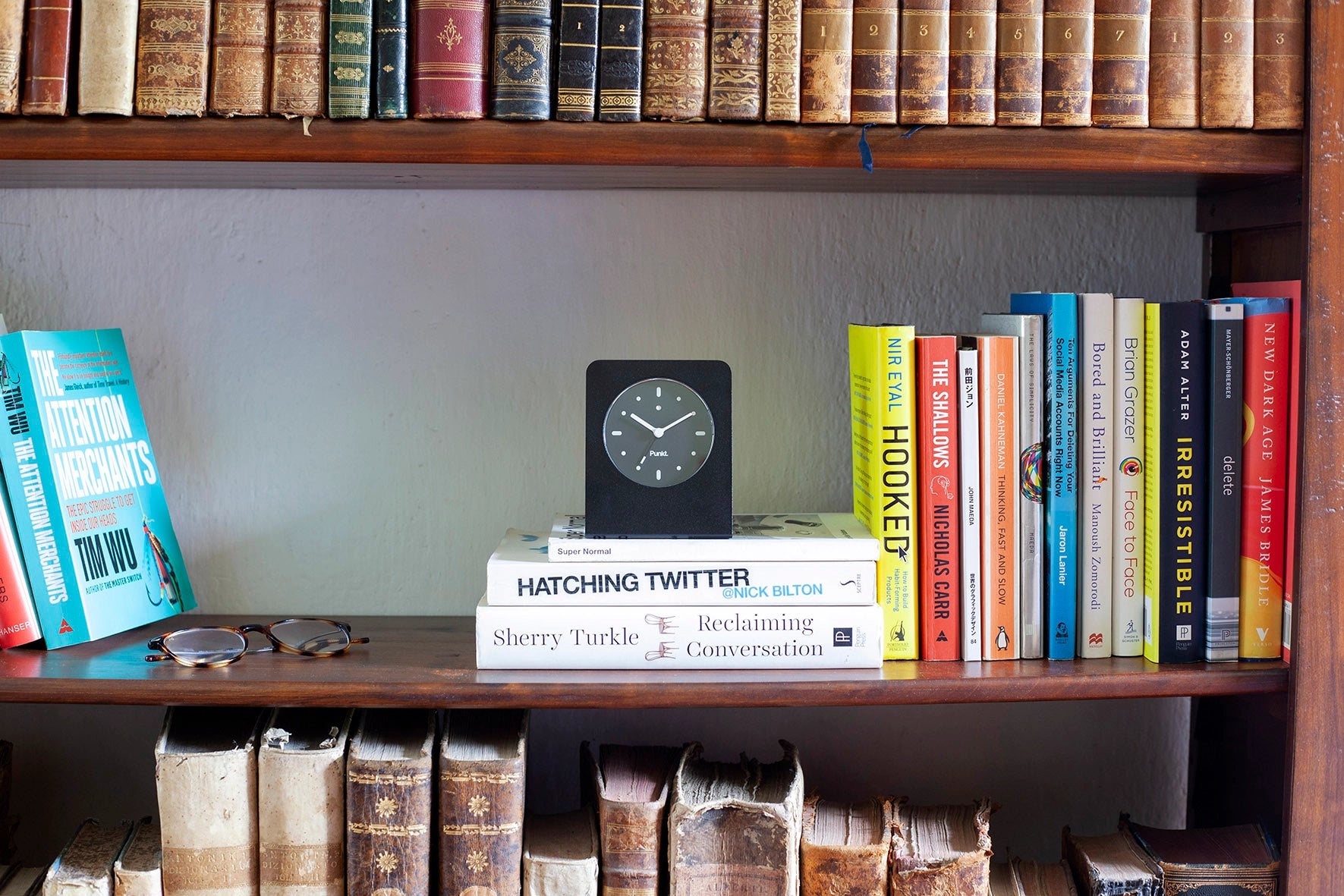 Black Punkt. AC02 sits on top of modern and vintage books on a wooden bookshelf.