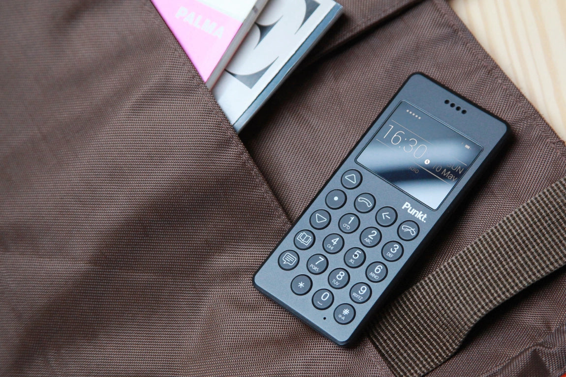 Punkt MP01 black phone partially tucked into a fabric bag pocket, highlighting its portability.
