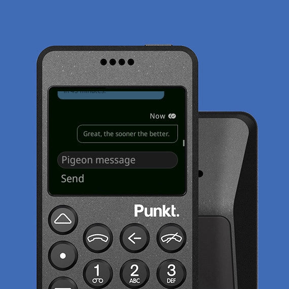 Front view of black Punkt. MP02 phone on blue background – Phone screen shows a chat message reading “Great, the sooner the better,” above a text input field labeled “Pigeon message.”