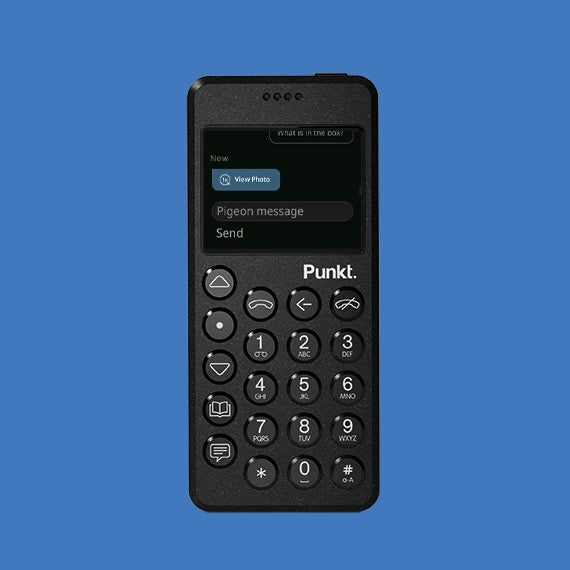 Black Punkt. phone on blue background – Front view of a black Punkt. MP02 minimalist mobile phone with round buttons and small display on a blue backdrop.