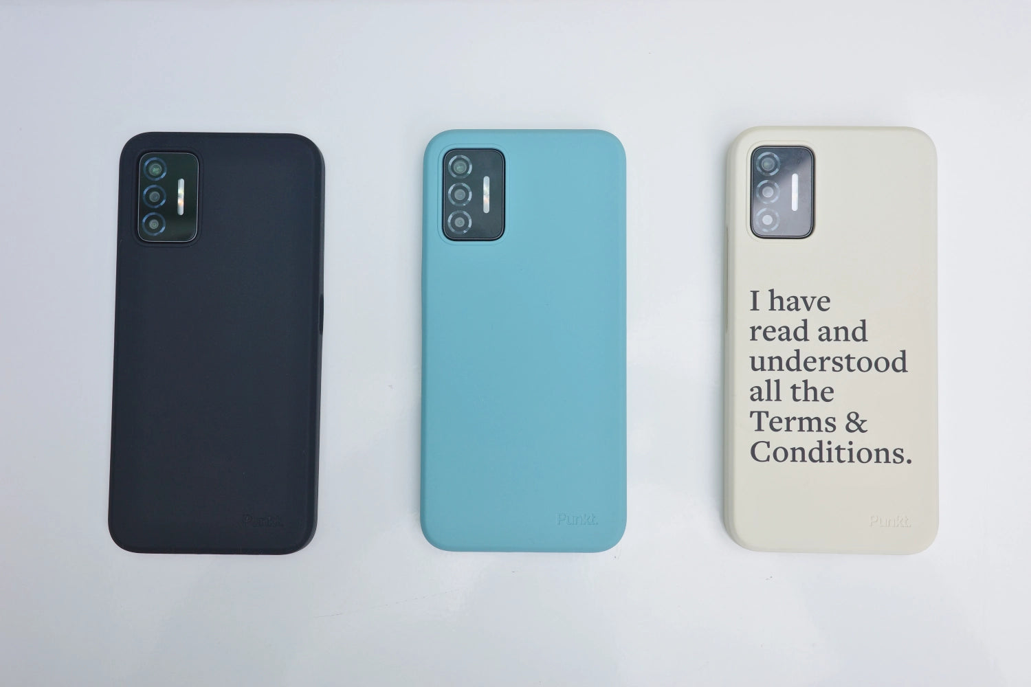 Top-down view of three Punkt. MC02 smartphones arranged in a row: black case on the left, light blue in the center, and cream case with printed message on the right.
