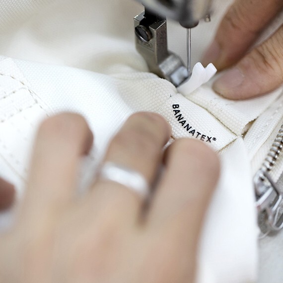 someone from QWSTION brand sewing a fabric case for Punkt. with the bananatex logo