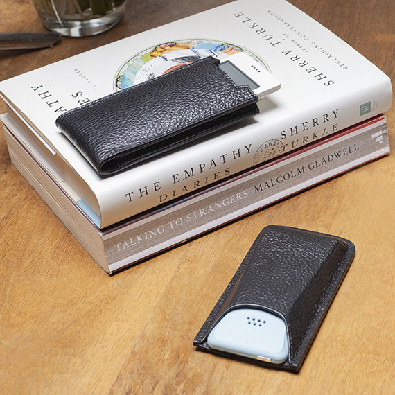 2 Danny P. leather MP02 cases with the MP02 light blue and the MP01 white on a wooden table next to some books