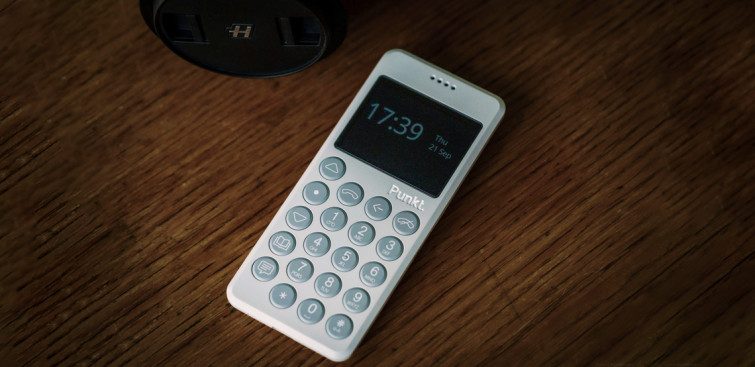 Punkt. mp02 light grey phone with time on the screen on a wooden table