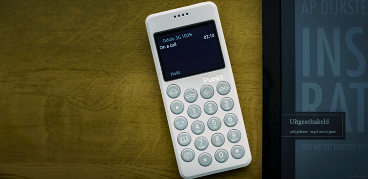 Punkt. mp02 light grey phone with time showing a call on a wooden table