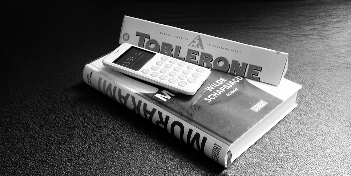 Punkt mp02 light grey on a book next a toblerone box